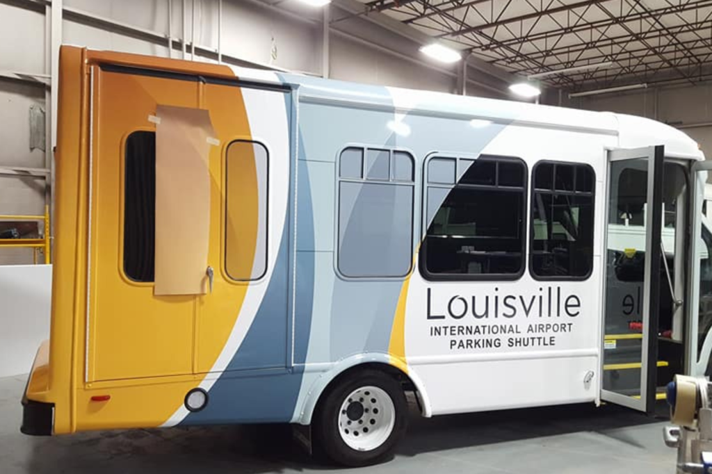 A Louisville city bus displaying the official logo, parked on a city street, ready for passengers.