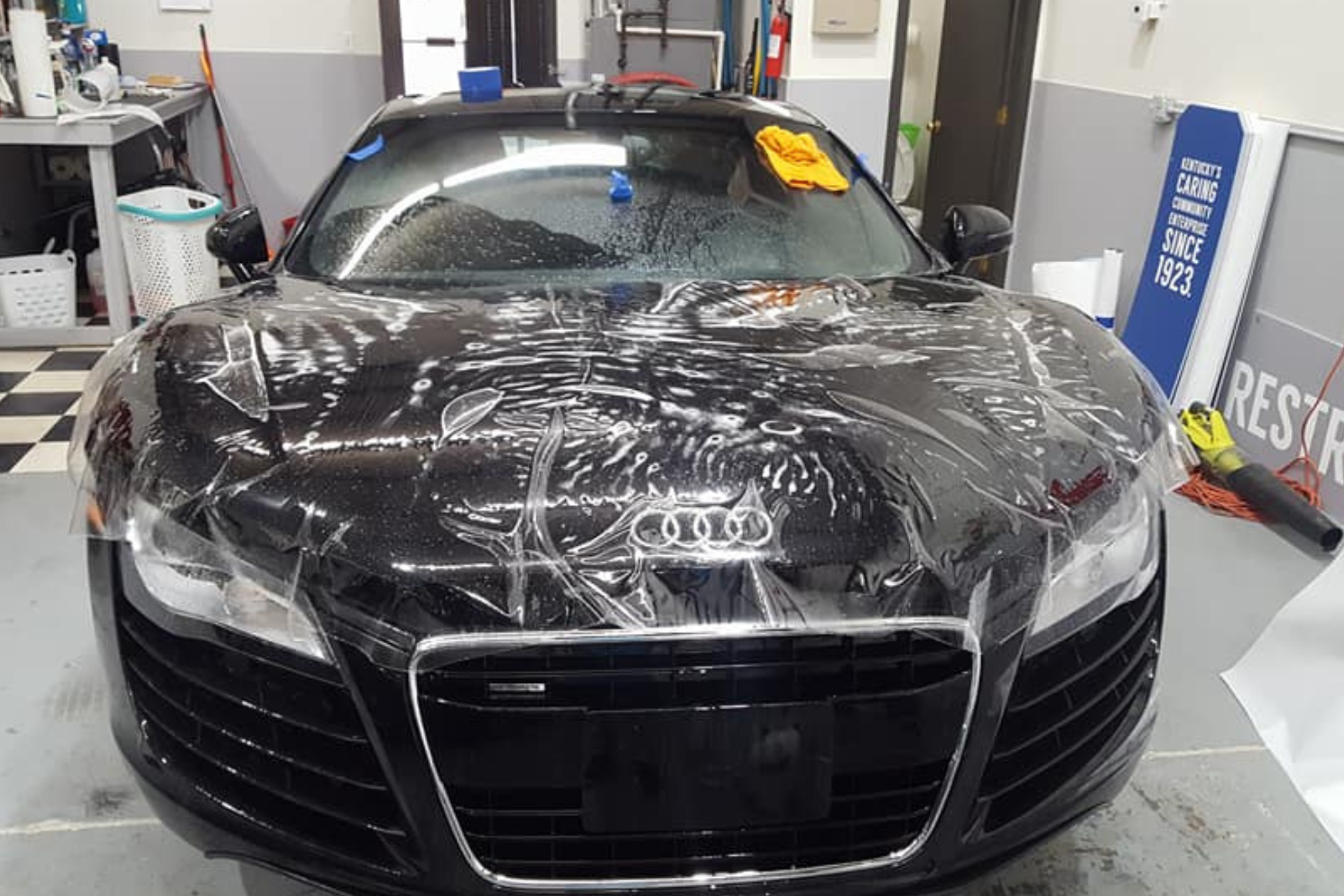 A black Audi car, covered in paint protection, presents a bold and artistic transformation of its original sleek design.